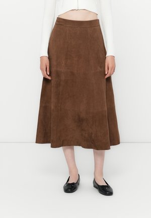 Brun semsket midi-skjørt med en glatt tekstur, flagrende design og et tettsittende liv. Båret med svarte ballerinasko.