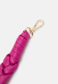 Bracelet en cuir tressé rose avec fermoir en métal doré fixé à une extrémité, sur fond clair uni.