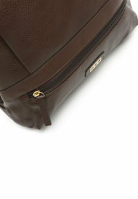 Rudono odos kuprinė su tekstūriniu paviršiumi, pasižyminti auksine užtrauktuku ir elegantišku dizainu. Išskirtiniai detaliai apima stačiakampį auksinį akcentą.