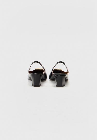 Black slingback heels with a rounded toe and chunky square heel. Smooth leather texture with a simple strap and gold accent detail.