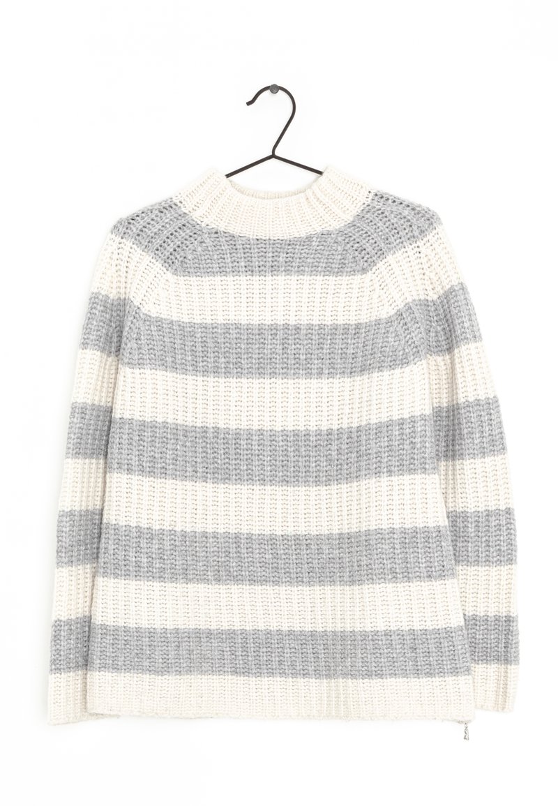 Pull en maille épaisse blanc et gris avec des rayures horizontales suspendu sur un cintre en métal noir sur fond blanc.