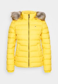 Żółta kurtka puchowa z odpinanym kapturem wyłożonym futerkiem, pikowanym wzorem, zamkiem błyskawicznym i ściągaczami przy rękawach. Na piersi znajduje się logo marki.