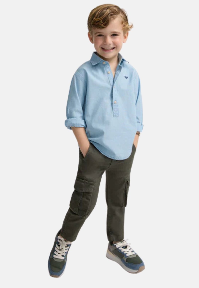 Camisa de manga larga celeste con cuello, pantalones cargo verdes oliva y zapatillas navy con cordones blancos. La camisa presenta un pequeño logo en el pecho.