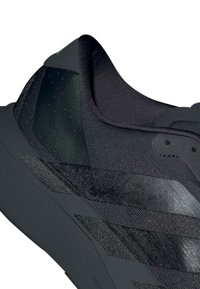 Κοντινή λήψη μιας μαύρης αθλητικής υποδήματος με υφαντό ύφασμα και παχύ πέλμα, με διακριτά γεωμετρικά σχέδια στο πλάι.