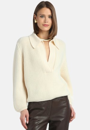 Knit pullover sweater in cream, featuring a wide collar, deep V-neckline, ribbed texture, and loose sleeves, paired with dark brown leather pants.