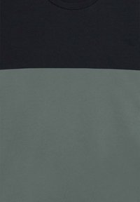 T-shirt a maniche corte con una parte superiore nera e una parte inferiore verde. Realizzato in morbido cotone, dotato di scollatura rotonda e texture liscia.