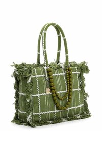 Zielona pleciona torebka w biały wzór w kratę, z frędzlami na brzegach i dwoma uchwytami. Ozdobiona zielonym naszyjnikiem z koralików.