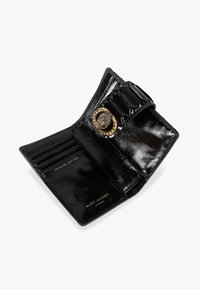 Czarny portfel z prawdziwej skóry z miejscami na karty i zapięciem w kształcie węża w kolorze złotym, sygnowany "Kurt Geiger London" wewnątrz.