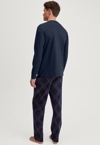 Marineblauw langemouwtop en geruite pyjamabroek in donkerblauw, bordeaux en wit; zachte katoenen stof; comfortabele pasvorm.