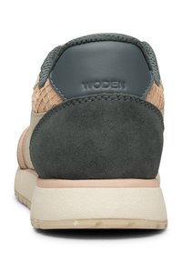 Sneakers featuring a textured olive green rear, peach suede accents, a mesh panel, and a beige rubber sole; brand name "WODEN" embossed.