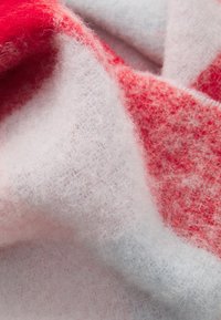 Zachte, fluffy stofvouwen met een rood en wit verlooppatroon, die gedetailleerde textuur en vezels in close-up weergeven.