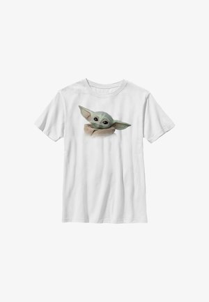 Hvid T-shirt med korte ærmer med trykt illustration af en lille, grøn, storøret karakter indsvøbt i en brun kappe foran.