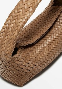 Sac en cuir tressé marron clair, avec une fermeture à rabat, présenté en gros plan sur un fond blanc.