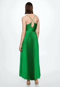Robe maxi plissée verte avec un corsage ajusté, des bretelles spaghetti réglables et une découpe ovale dans le dos. Le tissu a une texture douce.