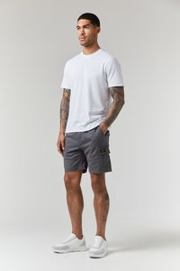 Graue Cargo-Shorts mit einer Seitentasche, kombiniert mit einem schlichten weißen Rundhalsausschnitt-T-Shirt und weißen Sneakern. Glatter Stoff, lässige Passform.