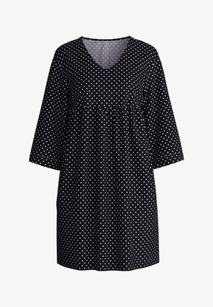 Zwarte jurk met witte stippen, V-hals en driekwartmouwen. Heeft een gebundelde taille voor een losse pasvorm.