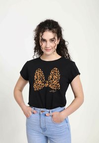 Schwarzes T-Shirt mit kurzen Ärmeln, das auf der Vorderseite ein großes Leopardenmuster-Bowdesign in Orange und Schwarz zeigt. Aus Baumwollstoff mit lockerer Passform.