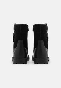 Schwarze Ankle Boots aus einer Mischung aus Wildleder und Leder. Das Design umfasst Reißverschlüsse an den Seiten und eine strukturierte Außensohle mit Branding.