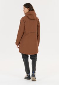 Bruine waterdichte parka met een capuchon, lange mouwen en een split aan de achterkant. Gemaakt van een gladde stof, met een logopatch op de mouw.