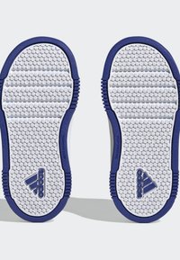 Suelas de goma blanca con agarre texturizado, acentos azules y características que no dejan marcas. Incluye el logo de Adidas en el talón y los lados.