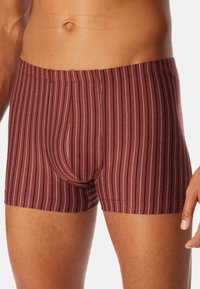 Rødt stribet boksershorts lavet af et blødt, tekstureret stof. Designet har smalle hvide og lysegrå striber samt en elastisk talje.