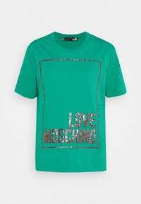 Grön t-shirt med kort ärm som har en glittrig roséguld rektangulär ram och texten "LOVE MOSCHINO" inuti rektangeln.