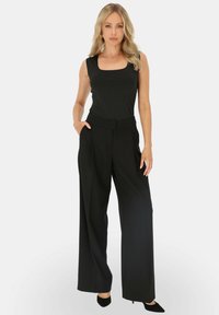Czarny top bez rękawów z kwadratowym dekoltem, zestawiony z czarnymi spodniami o wysokim stanie i szerokich nogawkach. Wyróżnia się gładkim materiałem i dopasowanym krojem.