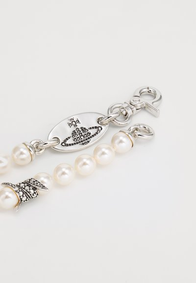 Bracelet en argent composé de perles blanches rondes, avec un accent en feuille d'argent texturée et un fermoir décoratif avec un logo et un détail en pierre précieuse.