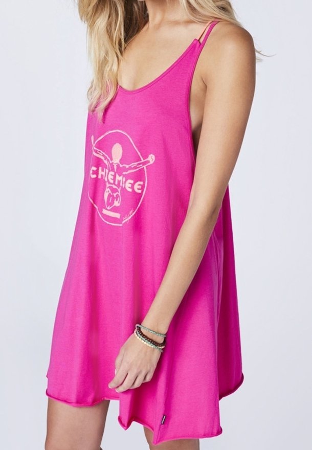 Femme portant une robe ample rose vif sans manches avec de fines bretelles et un logo graphique blanc sur le devant.