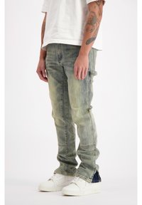 Licht gewashte denim jeans met een slim fit, voorzien van zijvakjes en een lichte vervaging. Gecombineerd met witte hoge sneakers.