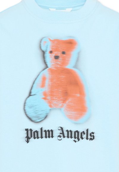 Chemise bleu clair présentant un ours en peluche bicolore duveteux en orange et bleu clair au-dessus du texte "Palm Angels" en police gothique noire.