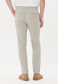 Light gray trousers with a check pattern, featuring a tailored fit, two back pockets, and cuffs rolled at the hem, worn with tan shoes.