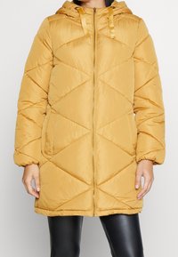 Gul, huva puffjacka med ett kviltat mönster med diamantformer, en blixtlås fram och sidofickor, tillverkad av ett slätt, syntetiskt tyg.