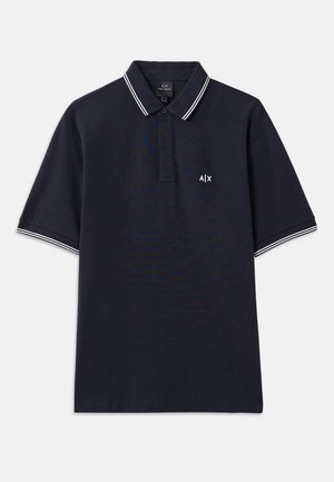 Polo azul marino de algodón con cuello clásico, tapeta de dos botones y acentos de rayas blancas en las mangas. Pequeño logo en el pecho.