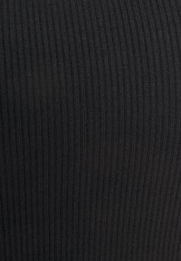 Tissu noir à côtes avec un motif texturé, affichant des lignes verticales qui créent un détail de surface subtil et invitant.