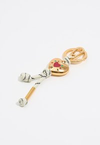 Llave en forma de corazón dorado con la inscripción "I ❤️ LAB", unida a un cordón trenzado blanco con rayas negras y detalles metálicos.