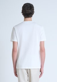 Camiseta de algodón blanca con mangas cortas y cuello redondo. Textura suave, sin patrones y dobladillo recto. Diseño sencillo y minimalista.