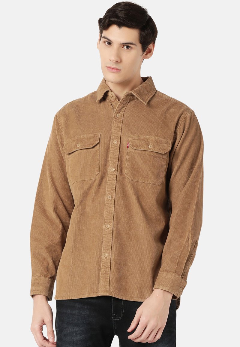 Brown corduroy shirt with long sleeves, button front, two chest pockets, and a small logo on the left pocket. Textured fabric design.