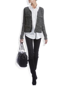 Černý a šedý pletený kardigan se dvěma předními kapsami, nošený přes bílou košili na knoflíky. Kombinován s černými úzkými džíny a černou kabelkou.