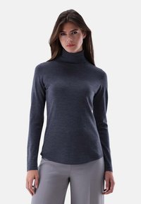 Dunkelgrauer Rollkragenpullover aus weichem Strickmaterial, mit langen �Ärmeln und leicht abgerundetem Saum, kombiniert mit hellgrauen Hosen.