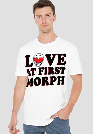 White cotton t-shirt featuring bold black text "LOVE AT FIRST MORPH" with a graphic of a helmet with a heart. Short sleeves, relaxed fit.
