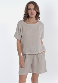 Completo due pezzi in lino beige chiaro composto da una blusa rilassata a maniche corte e pantaloni corti abbinati con tasche laterali e una leggera trama.