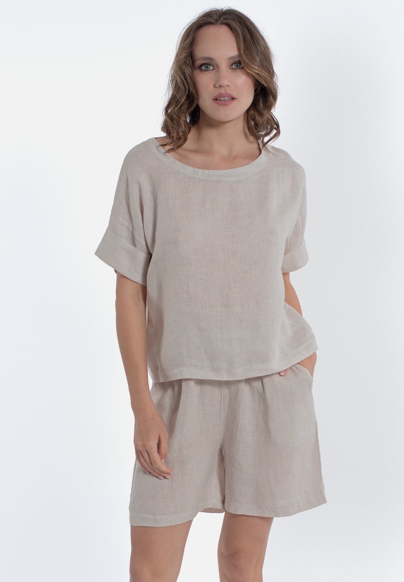 Completo due pezzi in lino beige chiaro composto da una blusa rilassata a maniche corte e pantaloni corti abbinati con tasche laterali e una leggera trama.