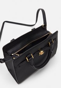 Sac à main en cuir noir texturé avec quincaillerie dorée, doubles poignées et sangle réglable. Comprend un compartiment zippé et une étiquette de marque intérieure.