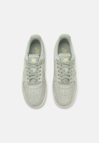 Paire de baskets Nike Air Force 1 gris clair avec lacets, boîte à orteils perforée, et logo Nike sur les languettes, vue de dessus sur fond blanc.