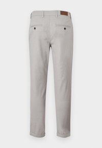 Ljusgrå byxor i texturerat tyg med rak skärning. Har två bakfickor med knappstängning och uppvikta manschetter.