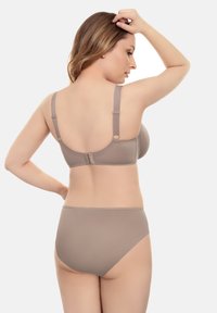 Sujetador beige y bragas a juego de talle alto. Tela suave, tirantes ajustables y cierre con gancho. Diseño sencillo sin patrones visibles.