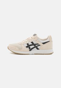 Beige színű sportcipő velúrból és hálós anyagból, fekete kiegészítőkkel, kerek orral, fűzős záródással és texturált gumitalppal.