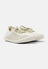 Lettskolet lette joggesko laget av beige mesh med teksturerte detaljer, elastiske snører og en fleksibel gummisåle. Rund tådesign.