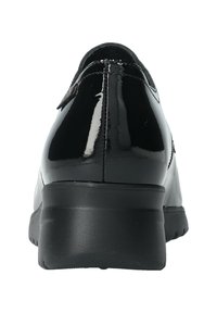 Chaussure en cuir verni noir avec un bout arrondi et un petit talon en caoutchouc, présentant une texture lisse et des détails de couture subtils sur le dessus.
